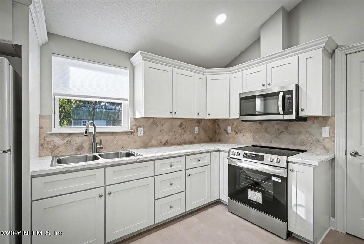 2210 Shepard Street Jacksonville, FL 32211 - Photo 15 of 29 a kitchen with white cabinets appliances and a sink