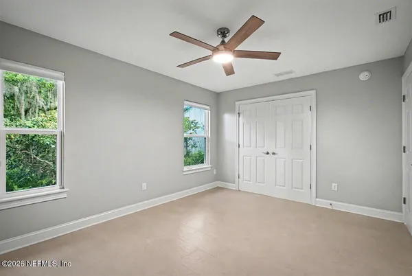 an empty room with windows and fan