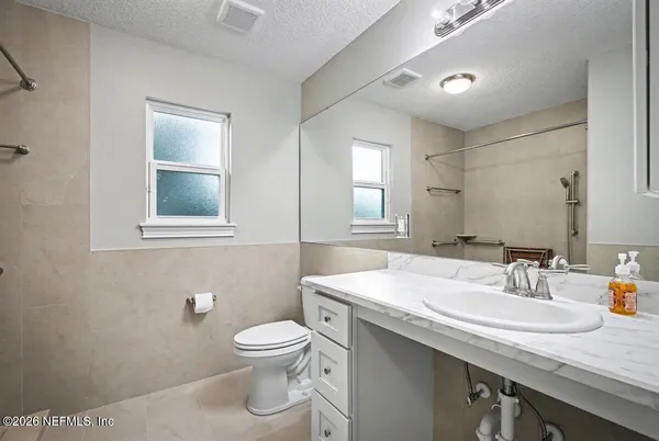 a bathroom with a granite countertop sink a toilet and mirror