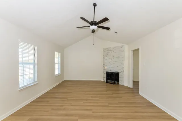 a view of empty room with fireplace and wooden floor