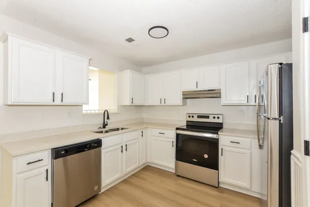 a kitchen with cabinets stainless steel appliances and wooden floor