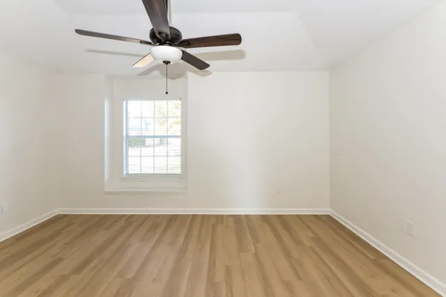 an empty room with a window and a chandelier fan