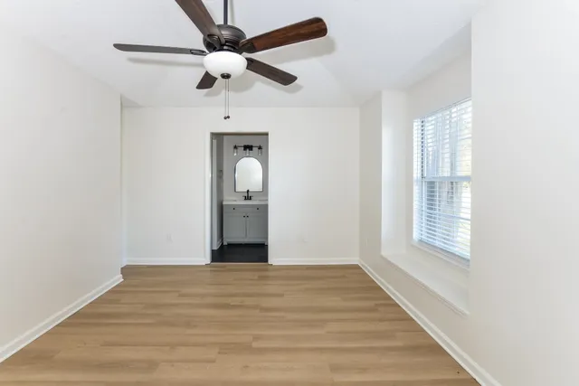a view of empty room with wooden floor and fan