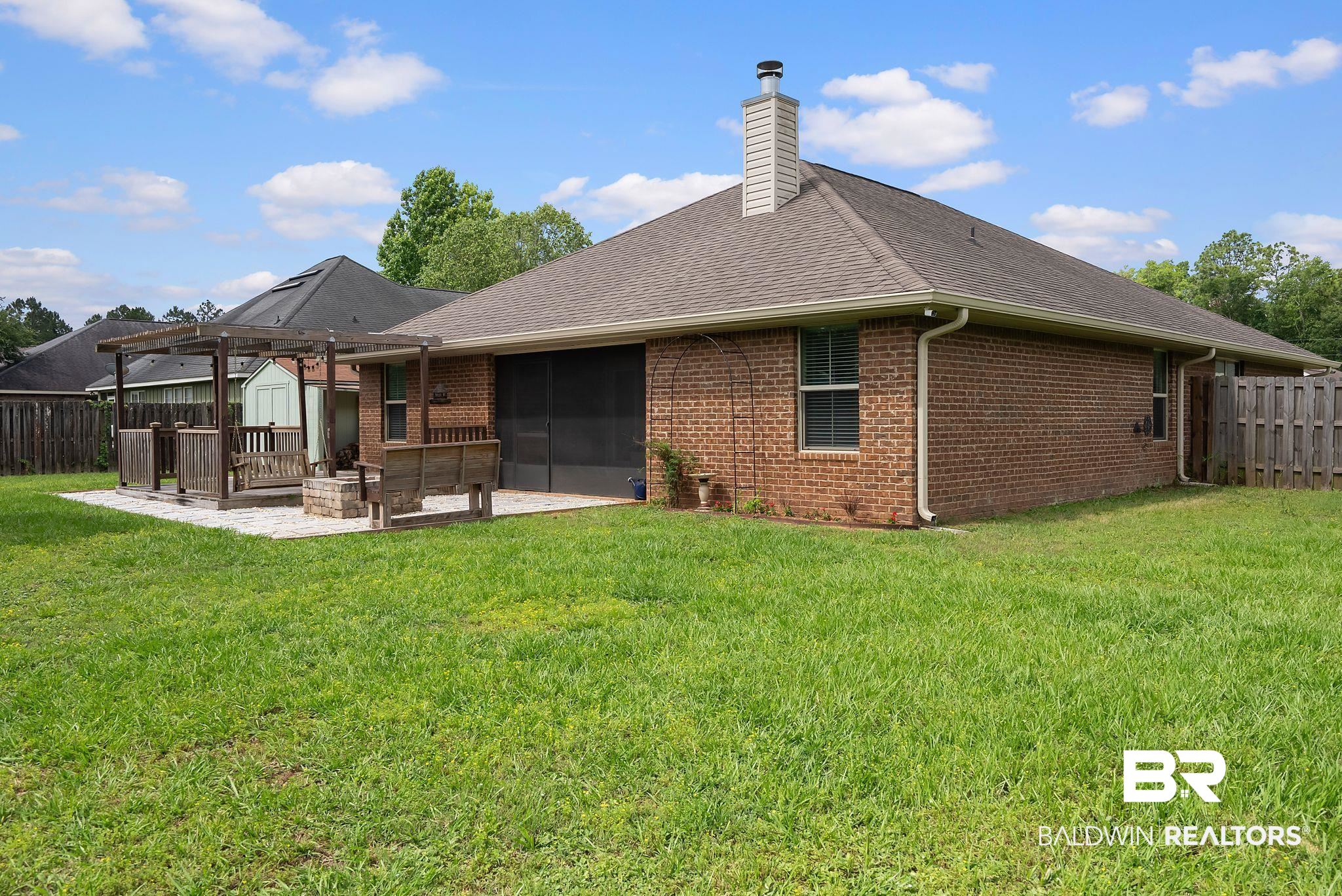 22076 Garland Loop Silverhill, AL 36576 - Photo 22 of 27 Expansive backyard featuring a brick exterior, screened patio, and a dedicated outdoor seating area with a pergola and stone-paver surface