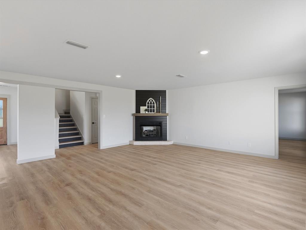 289 County Road 4655 Rhome, TX 76078 - Photo 7 of 34 Spacious interior featuring wide plank wood-finish flooring, black shiplap fireplace with wood mantle