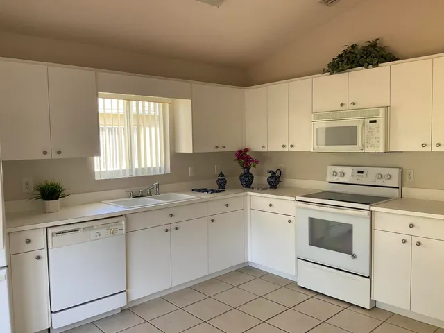 a kitchen with cabinets appliances a sink and a window