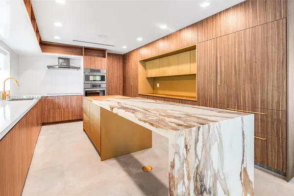 a view of kitchen with stainless steel appliances kitchen island wooden cabinets and entryway