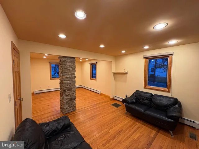a living room with couch and a glass table with wooden floor
