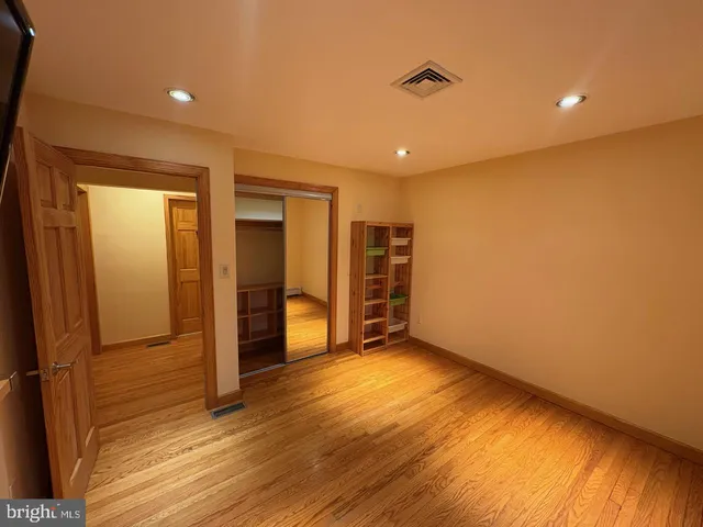 a view of an empty room with wooden floor and windows