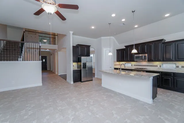 a open kitchen with stainless steel appliances granite countertop a refrigerator oven a sink dishwasher and white cabinets with wooden floor