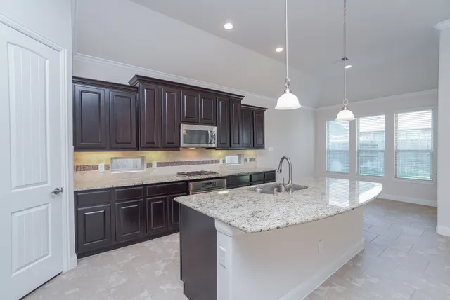 a kitchen with a stove a sink a center island and cabinets