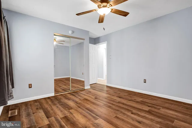 an empty room with wooden floor and fan