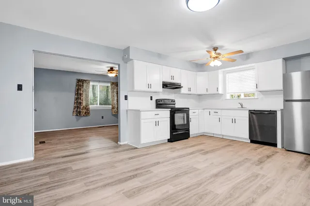 a kitchen with stainless steel appliances granite countertop a stove top oven a sink dishwasher and a refrigerator with wooden floor