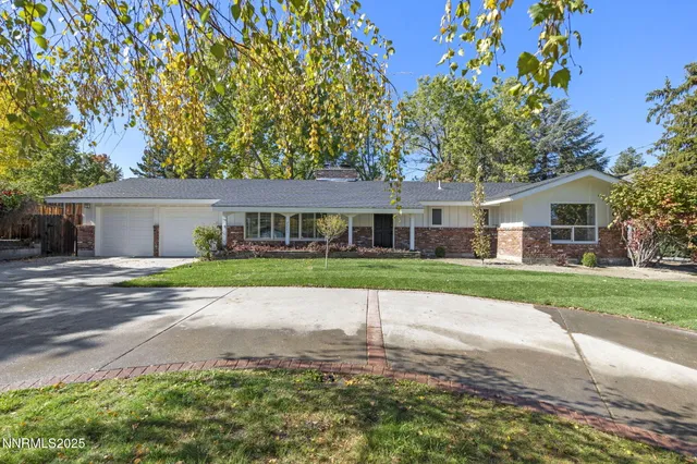 a view of house in front of a big yard with large trees