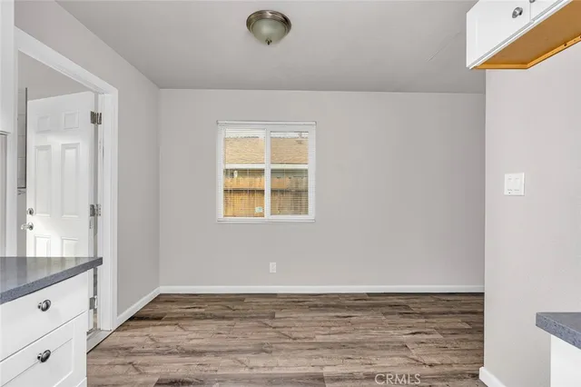 a view of an empty room with window and wooden floor