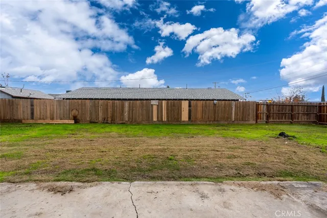 a view of a yard with grass and wooden fence
