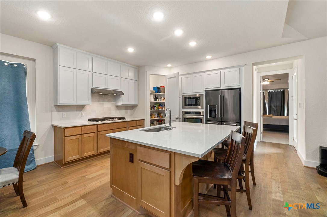 1845 Nettletree Road New Braunfels, TX 78132 - Photo 12 of 33 a kitchen with stainless steel appliances granite countertop a table chairs sink refrigerator and cabinets