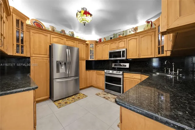 a kitchen with stainless steel appliances granite countertop a refrigerator a stove and a sink with wooden floor