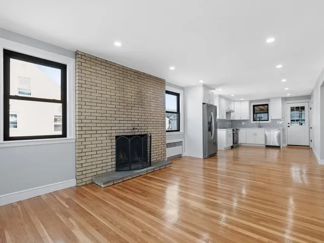 an empty room with wooden floor and fireplace