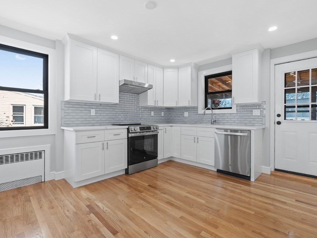 48 Albert Street Waltham, MA 02453 - Photo 9 of 37 a kitchen with stainless steel appliances kitchen island granite countertop a sink cabinets and wooden floor