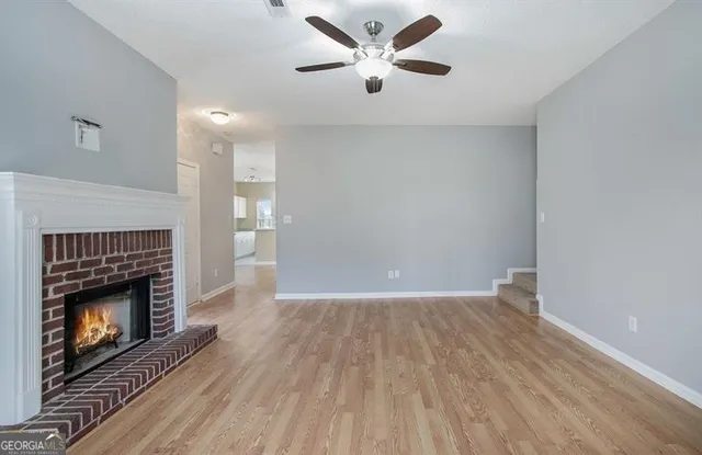 a view of an empty room with wooden floor a fireplace and a window