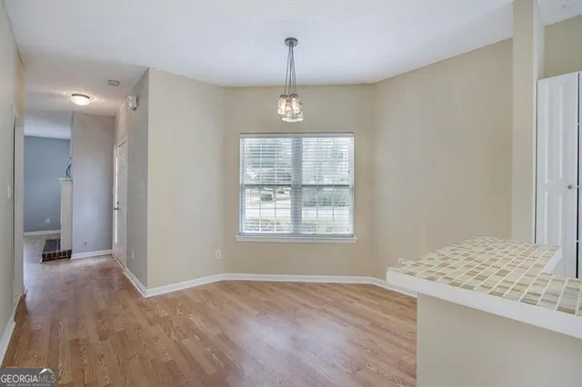 a view of an empty room with window and wooden floor