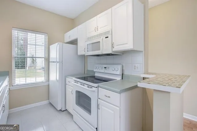 a kitchen with granite countertop white cabinets and white appliances