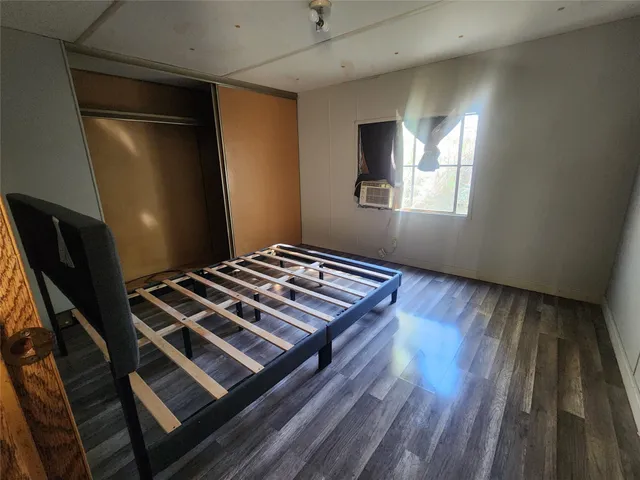 a bedroom with wooden floor and a window