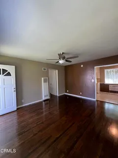 a view of an empty room with wooden floor and a window