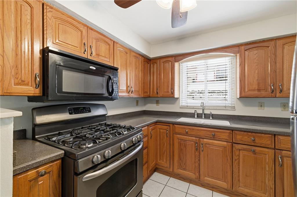 1368 Cathell Road Pittsburgh, PA 15236 - Photo 11 of 28 a kitchen with granite countertop a stove a sink and dishwasher wooden cabinets with wooden floor