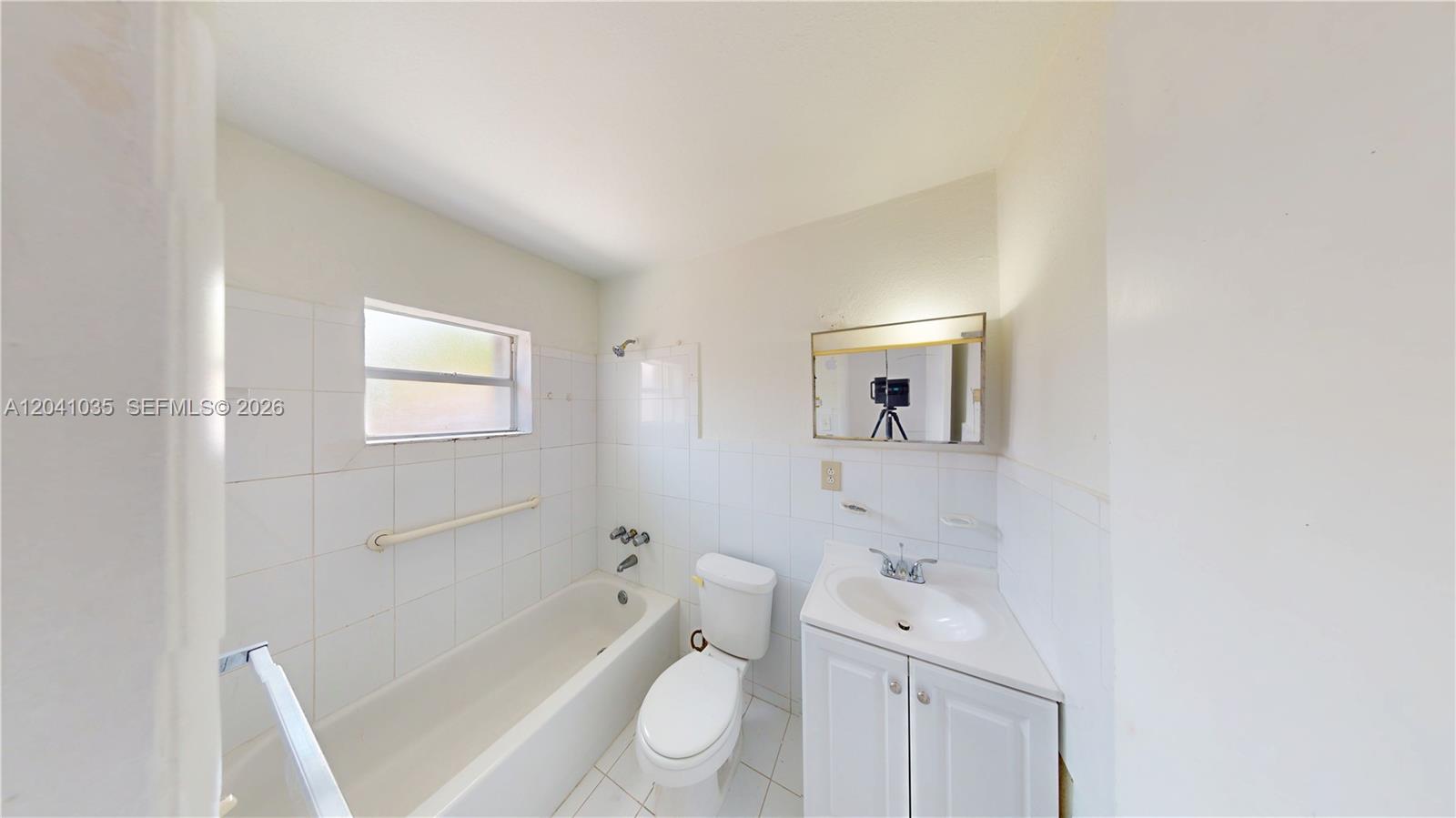 6811 Southwest 16th Street Miami, FL 33144 - Photo 18 of 21 a bathroom with a toilet a sink a mirror and a bathtub