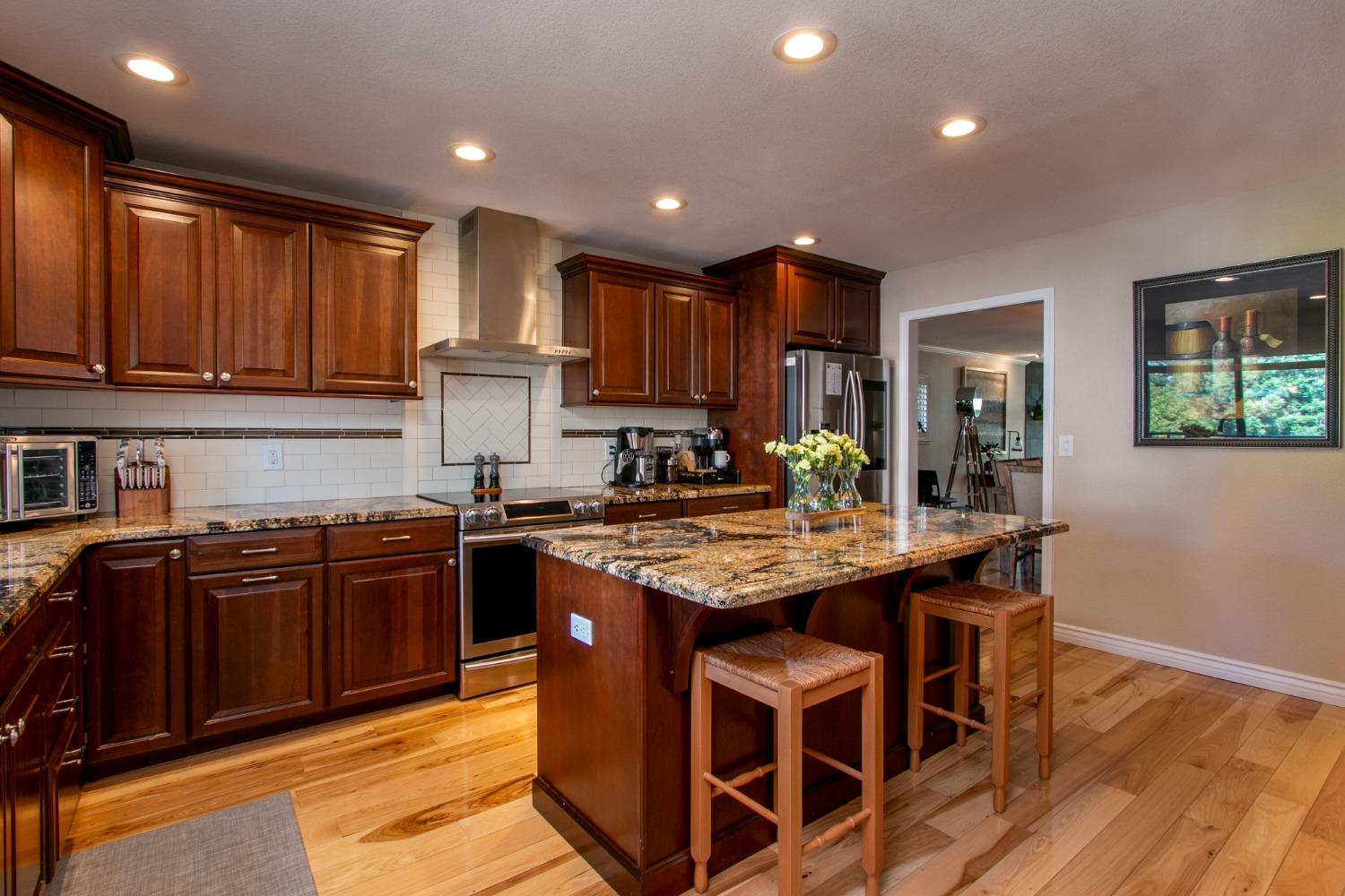 14975 Lago Drive Rancho Murieta, CA 95683 - Photo 6 of 41 a kitchen with stainless steel appliances granite countertop wooden cabinets a stove top oven and a granite counter top