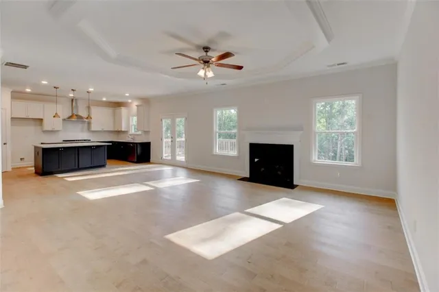 view of a livingroom with a fireplace a ceiling fan and wooden floor