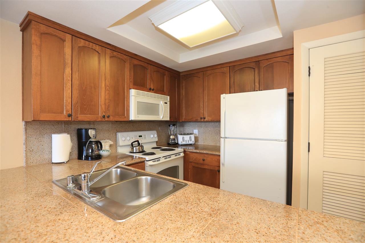 4401 Lower Honoapiilani Road, Unit B501 Lahaina, HI 96761 - Photo 8 of 14 a kitchen with a refrigerator sink and cabinets
