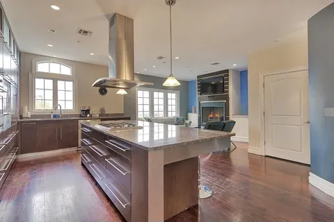 a kitchen with stainless steel appliances granite countertop a stove a sink and a wooden floors