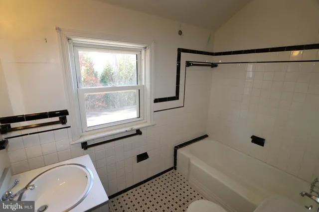 a bathroom with a sink a toilet a window and shower