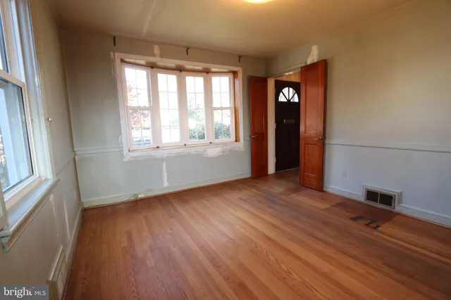 an empty room with wooden floor and windows