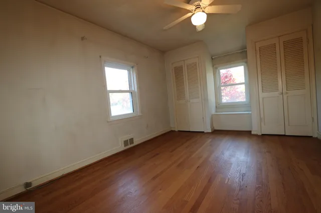an empty room with wooden floor and windows