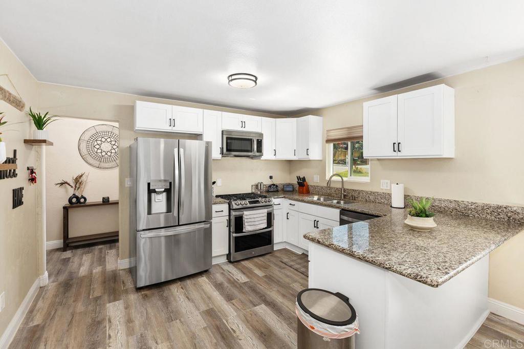 8229 Medill Avenue El Cajon, CA 92021 - Photo 5 of 34 a kitchen with granite countertop a refrigerator a stove a sink dishwasher and white cabinets with wooden floor