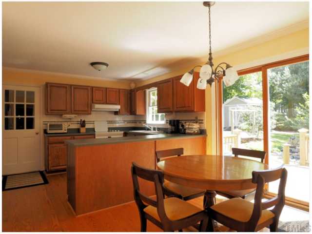 6208 Dresden Lane Raleigh, NC 27612 - Photo 3 of 25 a kitchen with stainless steel appliances granite countertop a stove top oven a sink a dining table and chairs with wooden floor