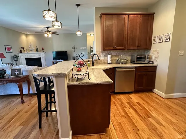 a kitchen with stainless steel appliances granite countertop a sink dishwasher and a stove with wooden floor