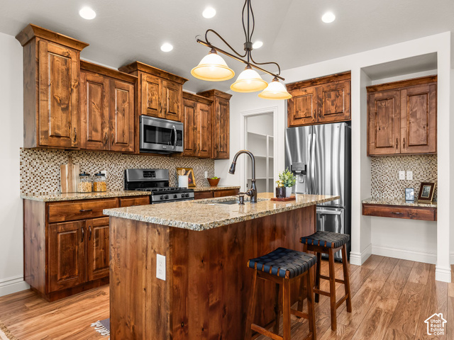 Kitchen featuring wood-finish flooring, custom wood cabinetry, granite countertops, and stainless steel appliances