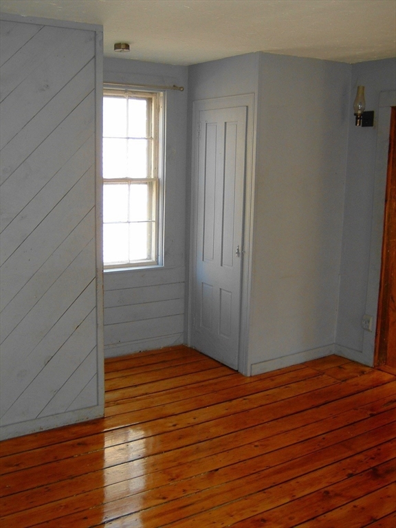 128 Pleasant Street, Unit 2 Marblehead, MA 01945 - Photo 5 of 13 an empty room with wooden floor and windows