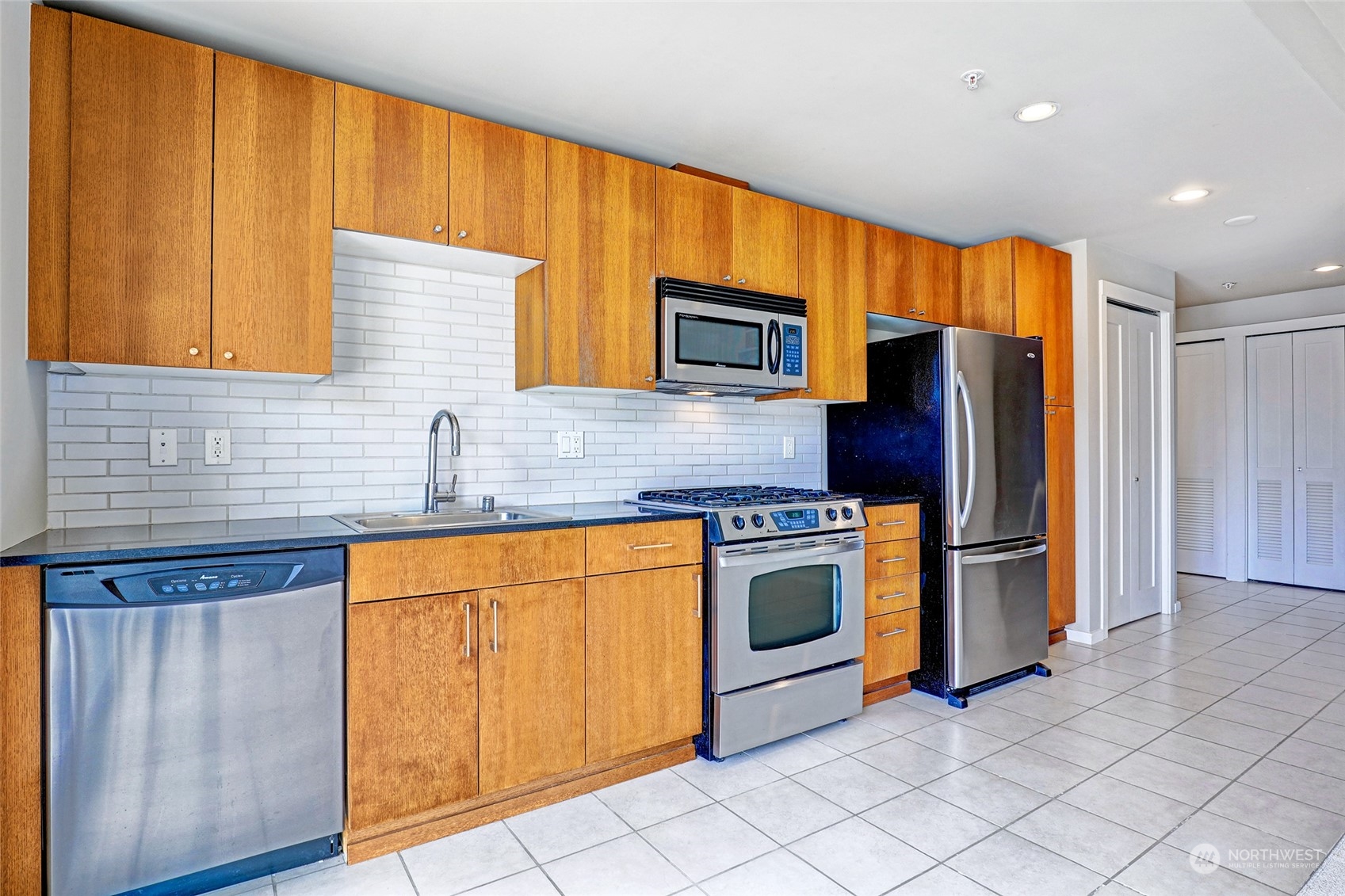 76 Cedar Street, Unit 710 Seattle, WA 98121 - Photo 3 of 20 a kitchen with stainless steel appliances granite countertop a refrigerator a sink dishwasher and wooden cabinets with a dishwasher
