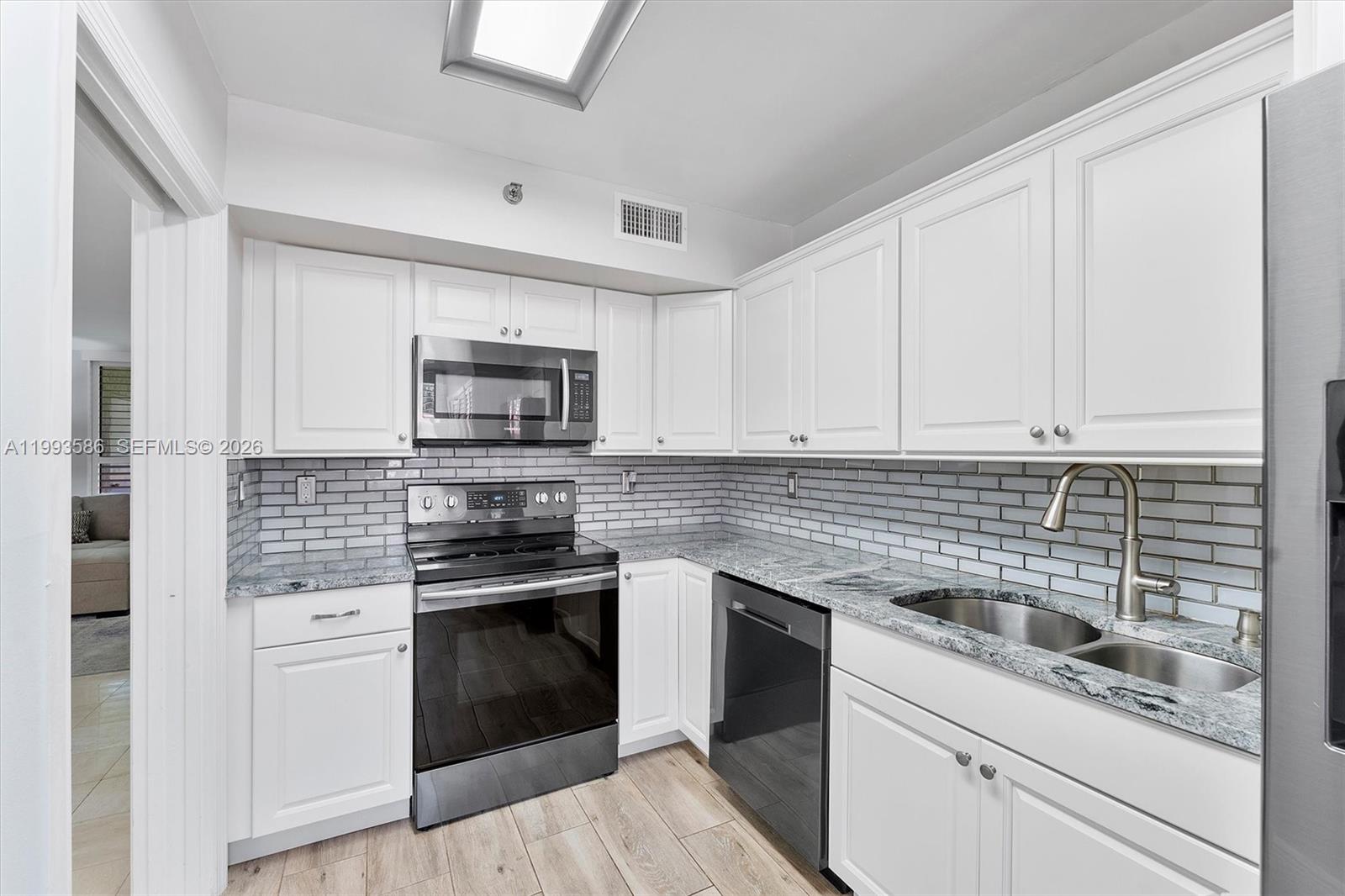 7225 Promenade Drive, Unit 102 Boca Raton, FL 33433 - Photo 8 of 21 a kitchen with white cabinets stainless steel appliances and sink