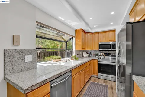 a kitchen with stainless steel appliances granite countertop a sink a stove and a refrigerator