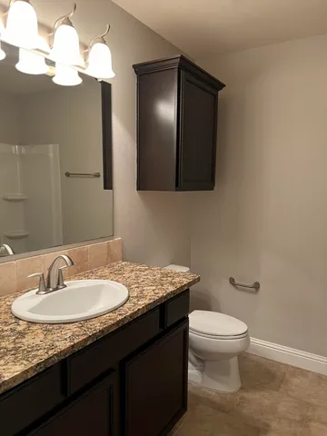 a bathroom with a granite countertop sink a toilet and a mirror