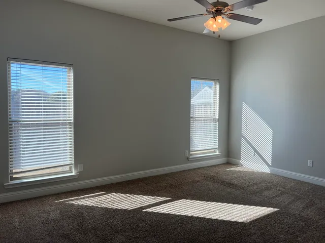 an empty room with windows and fan