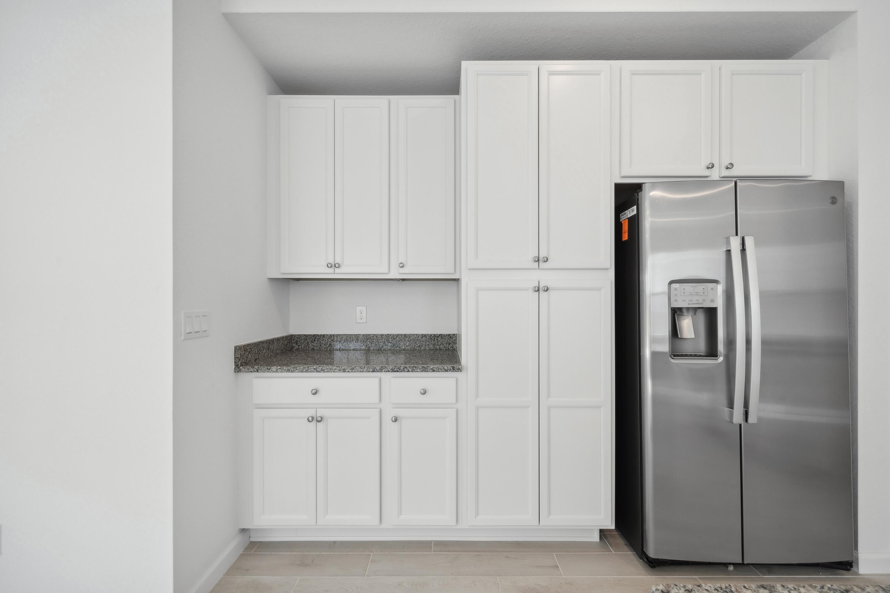 10099 Dreamweaver Road, Unit 51 Port St. Lucie, FL 34987 - Photo 9 of 36 a kitchen with white cabinets and refrigerator