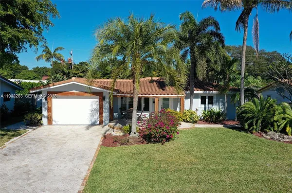 a front view of a house with a garden and tree